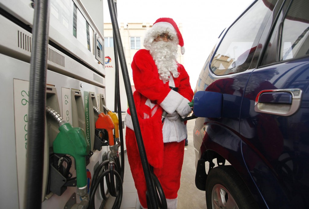 Papai Noel abastecendo seu carro junto a bomba de combustível 