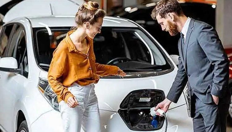 Vendedor explica à consumidora como é fácil carregar a bateria de carro elétrico (foto: autoo.com.br)